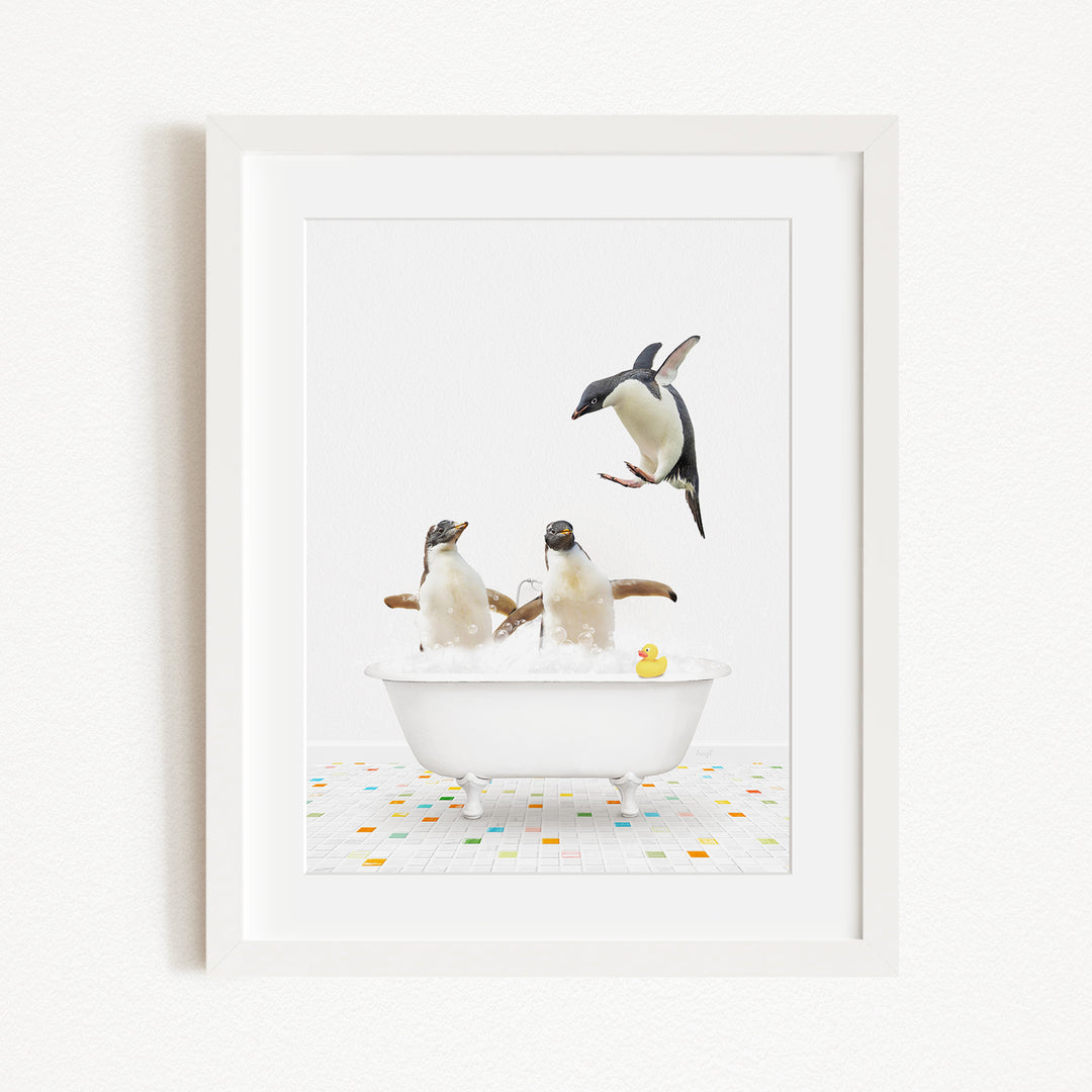 A framed image depicting two penguins sitting in a bathtub, with one penguin jumping out of the tub and another penguin sitting in the tub.