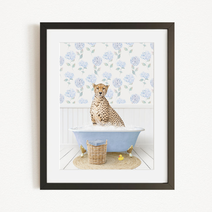 A cheetah sitting in a blue bathtub filled with water, surrounded by a floral patterned wall and a basket of rubber ducks.