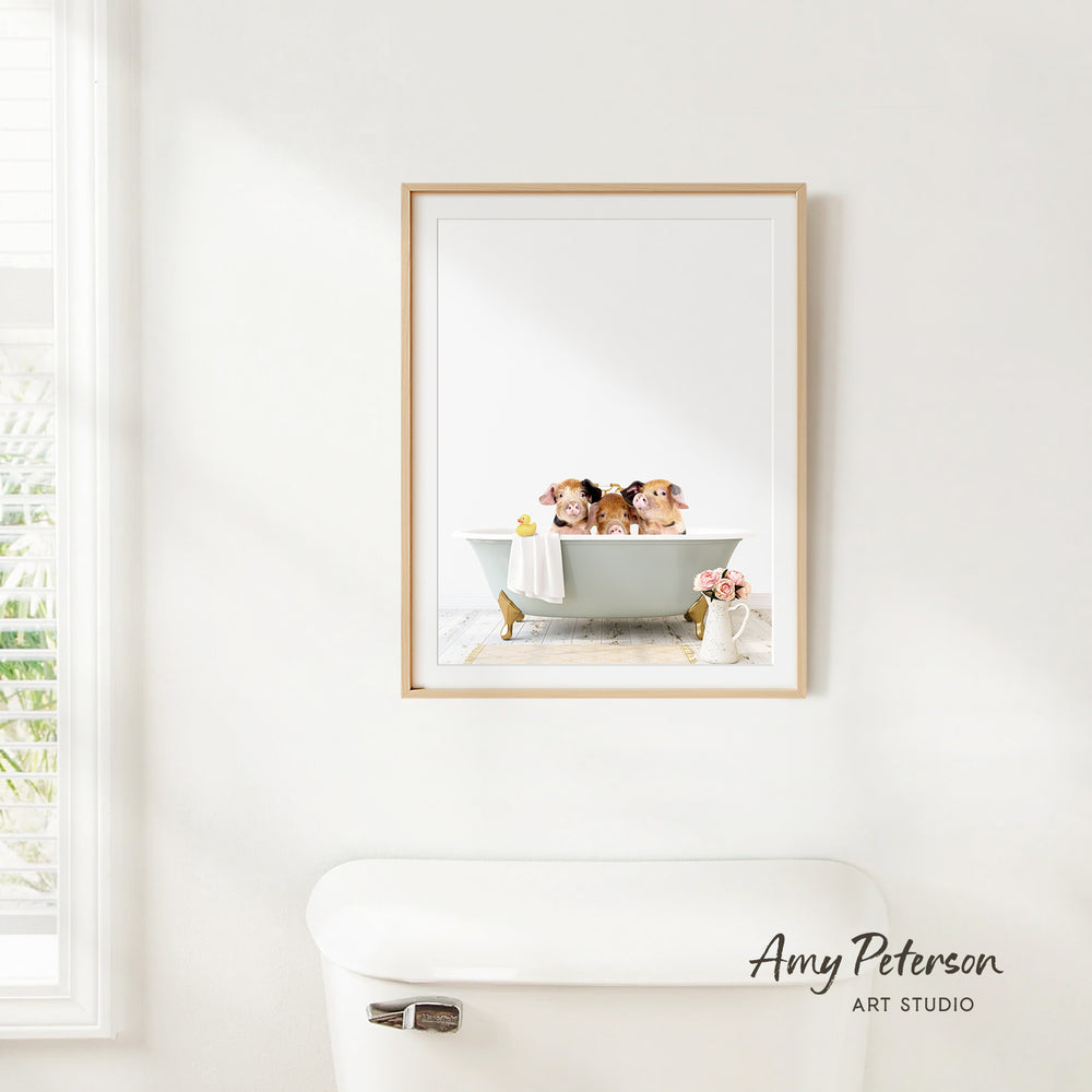 A framed image of three small dogs sitting in a bathtub, with a white toilet and a window in the background.