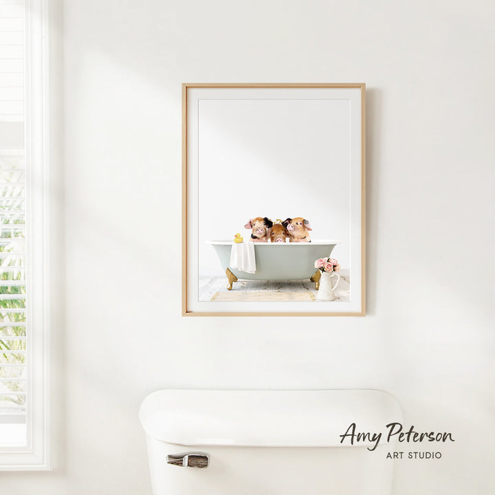 A framed image of three small dogs sitting in a bathtub, with a white toilet and a window in the background.