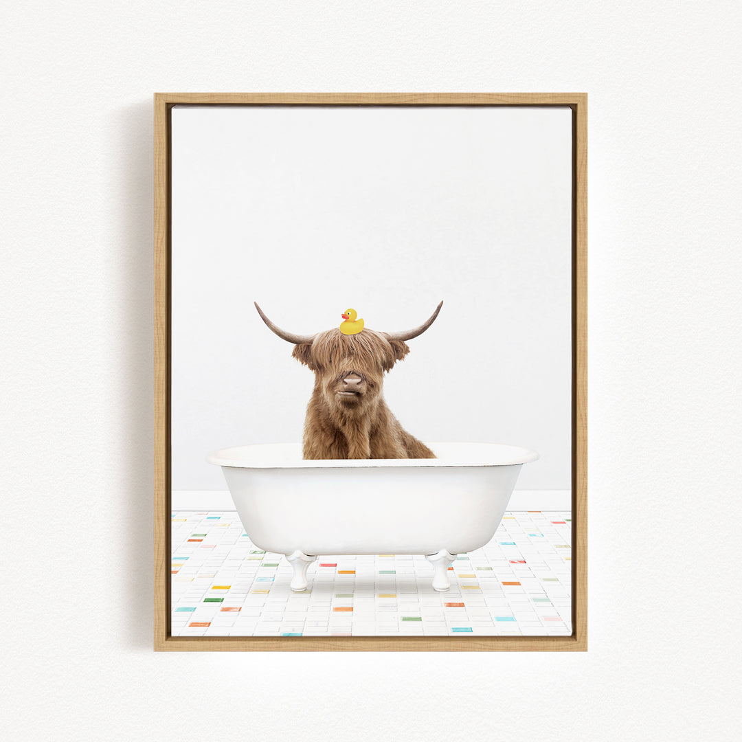 A brown cow with long horns is sitting in a white bathtub, with a rubber duck perched on its head.