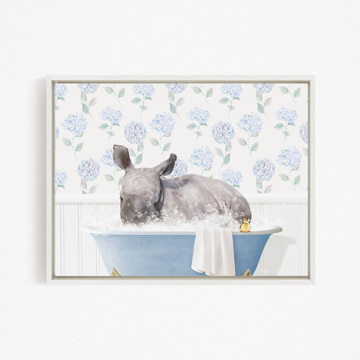 A rhinoceros is sitting in a blue bathtub filled with water, surrounded by a floral pattern on the wall behind it.