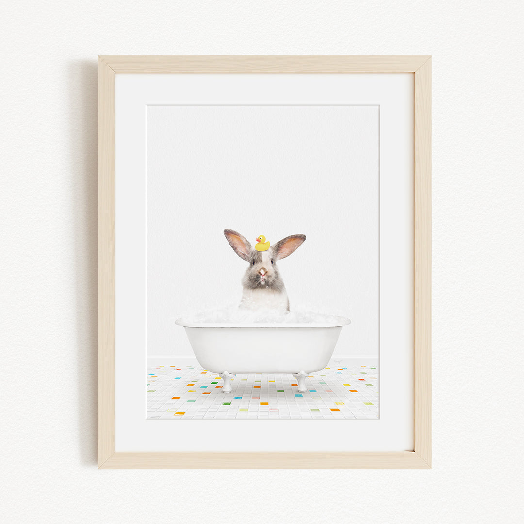 A white rabbit sitting in a white bathtub filled with bubbles, surrounded by colorful tiles on the floor.