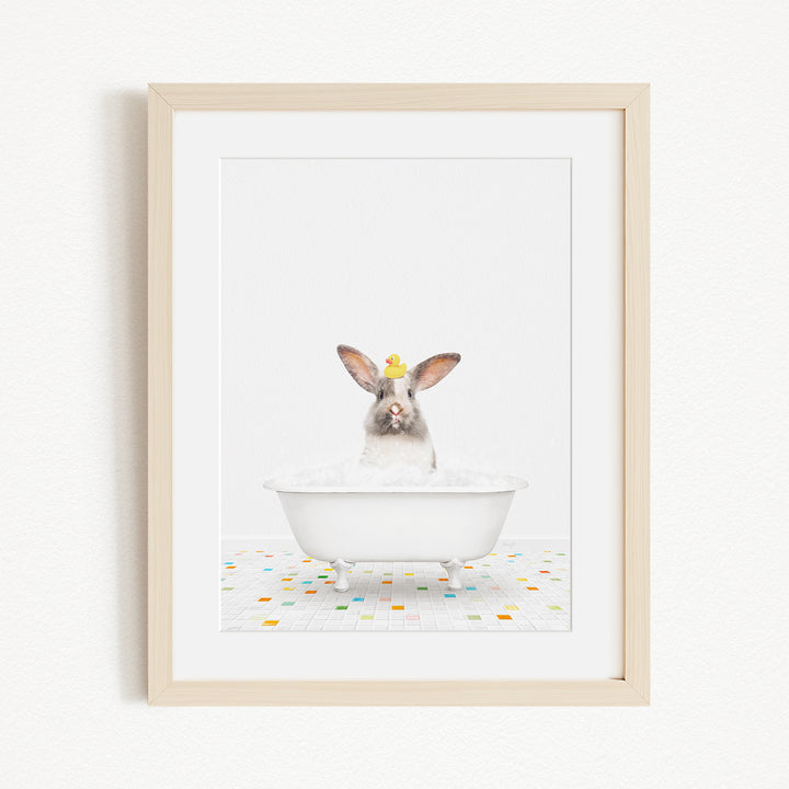 A white rabbit sitting in a white bathtub filled with bubbles, surrounded by colorful tiles on the floor.