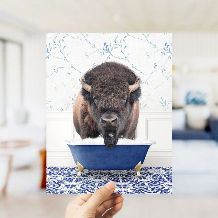 A large, furry bison with horns is sitting in a blue bathtub, surrounded by a blue and white patterned floor.