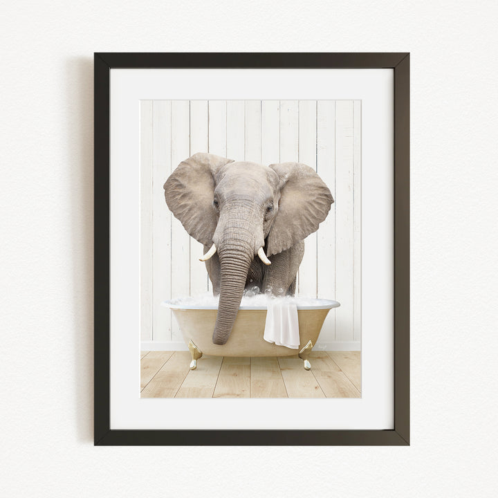 A gray elephant is sitting in a white bathtub, with its trunk extended towards the water.