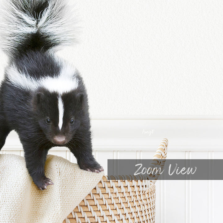 A young black and white striped skunk is standing on a woven basket, with a white wall in the background.