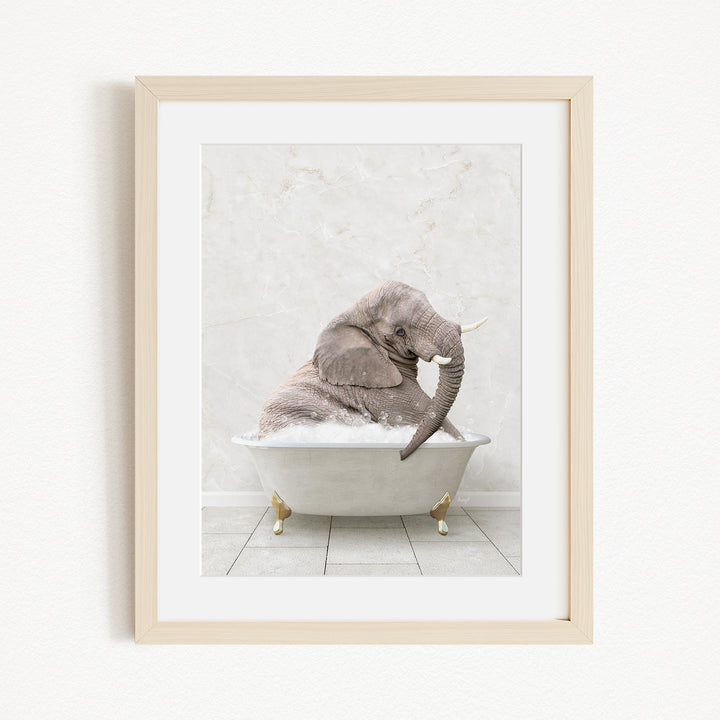 A gray elephant is sitting in a white bathtub, with its trunk raised and appearing to be enjoying the bath.