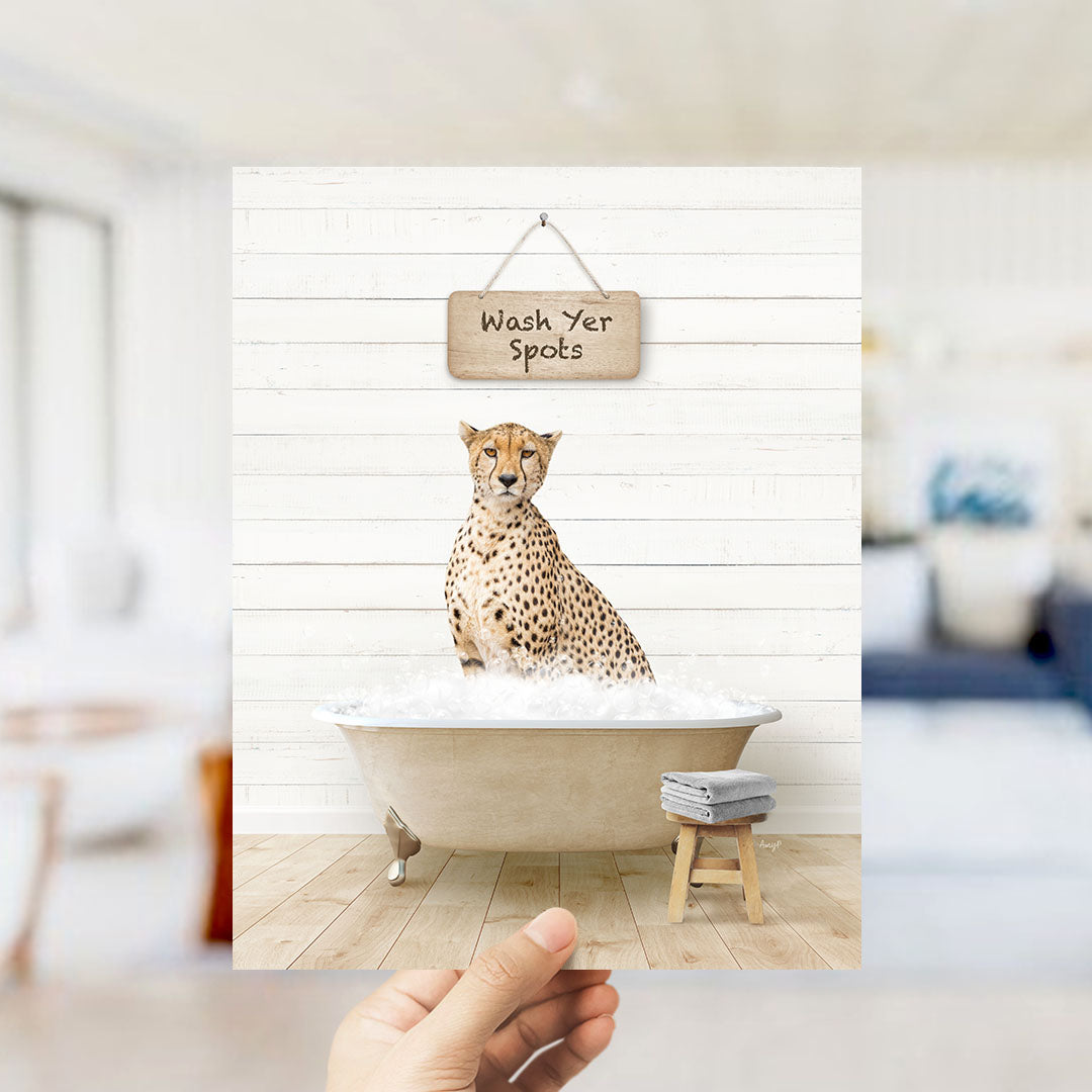 A cheetah sitting in a bathtub filled with water, with a sign above it that says "Wash Your Spots".