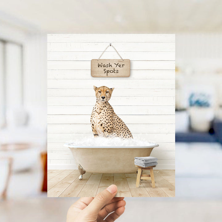 A cheetah sitting in a bathtub filled with water, with a sign above it that says "Wash Your Spots".