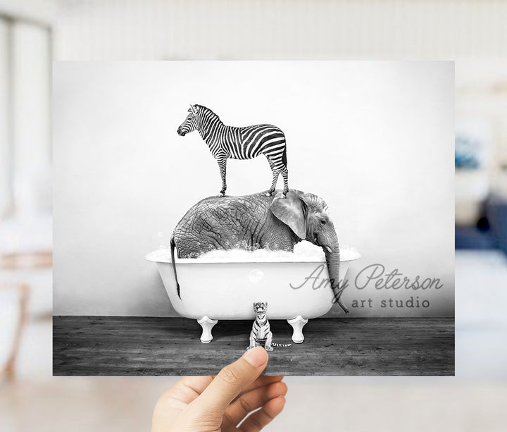 a person holding up a picture of a zebra and an elephant in a bathtub