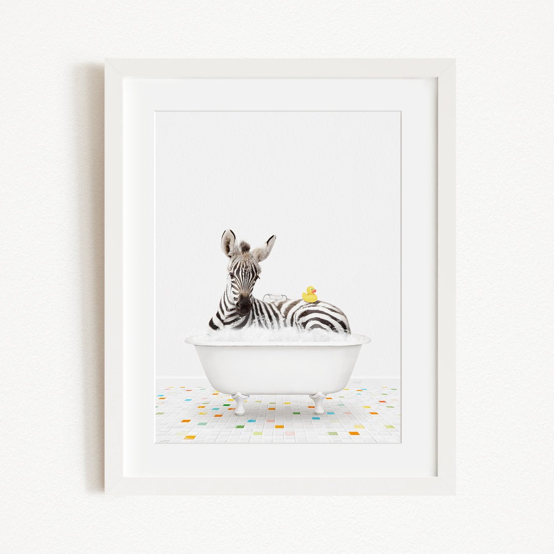 A zebra is sitting in a white bathtub, surrounded by a yellow rubber duck.