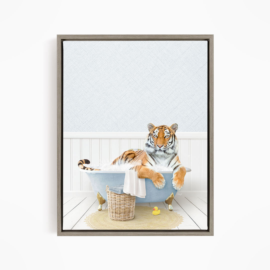 A tiger is sitting in a bathtub filled with water, surrounded by a basket of toys and a yellow rubber duck.