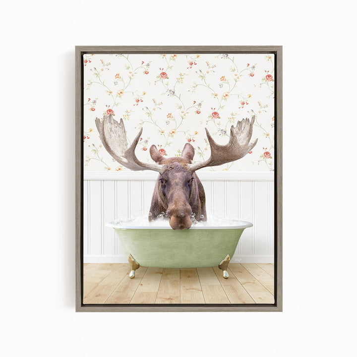 A moose with large antlers is sitting in a green bathtub, surrounded by a floral wallpaper.