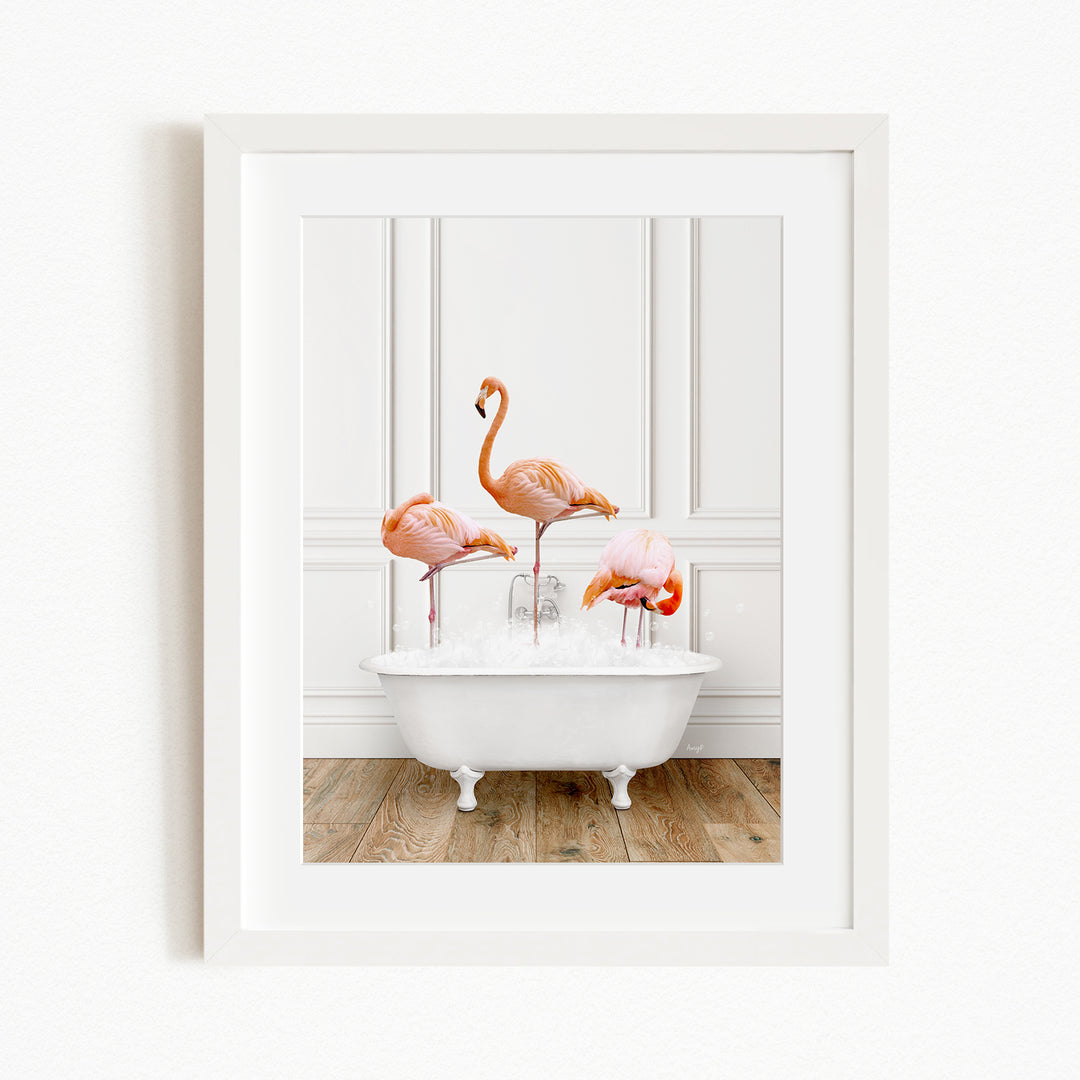 A framed image of three flamingos standing in a white bathtub filled with water.