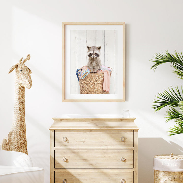 a raccoon sitting in a woven basket, which is hanging on a wall above a wooden dresser.