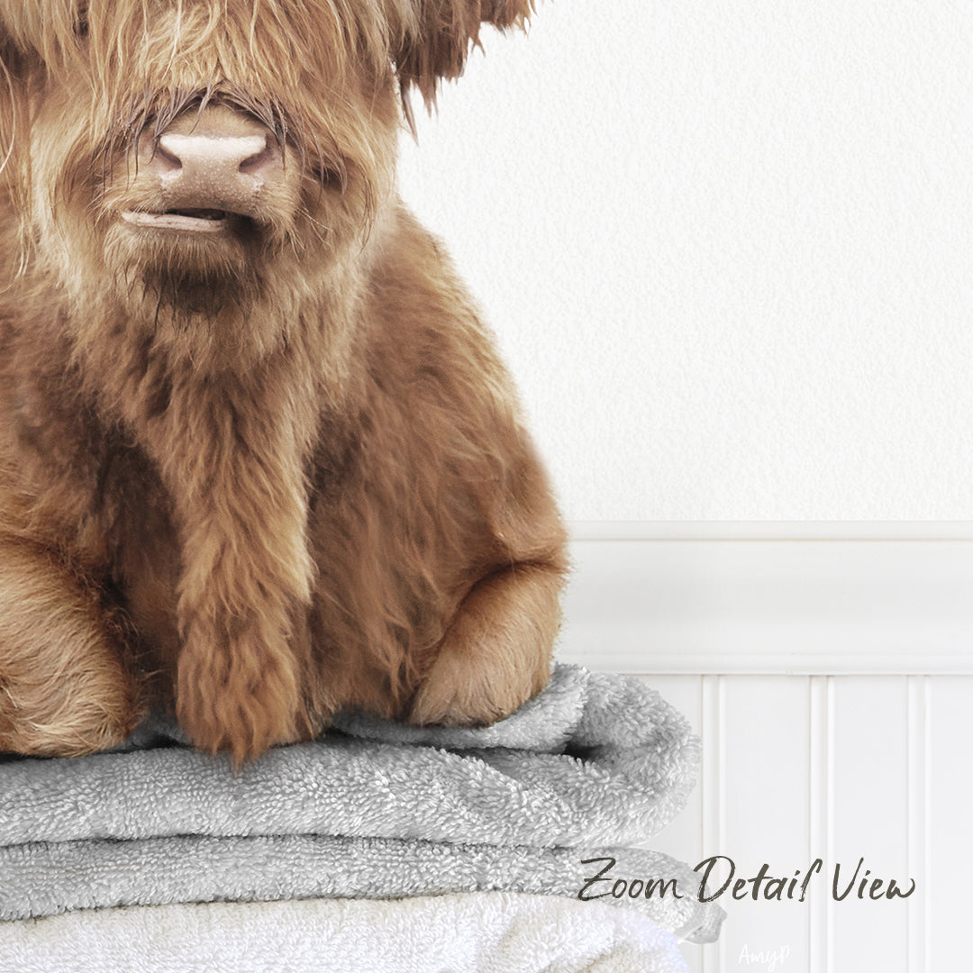 A close-up image of a furry brown animal, possibly a dog or a cat, sitting on top of a stack of towels.