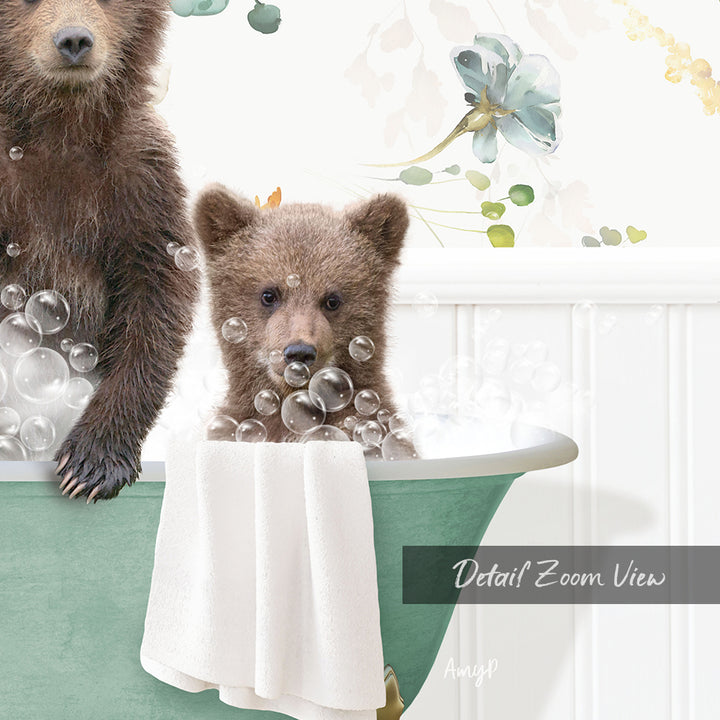 A baby bear sitting in a bathtub filled with bubbles, with a towel draped over the side of the tub.