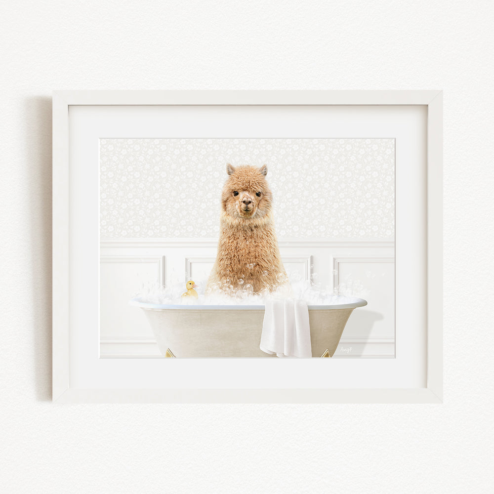 A brown alpaca sitting in a white bathtub filled with bubbles, with a yellow rubber duck floating in the water.