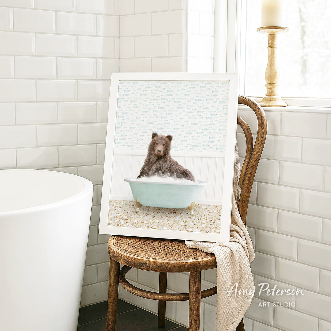 A framed image of a bear sitting in a bathtub, surrounded by a light blue and white patterned background.