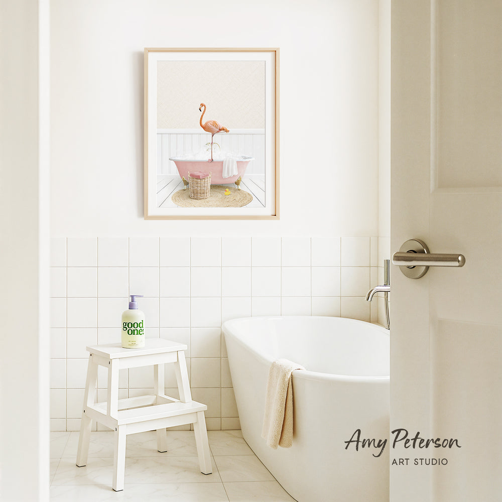 a bathroom with a white bathtub, a stool, and a framed picture of a pink flamingo on the wall.