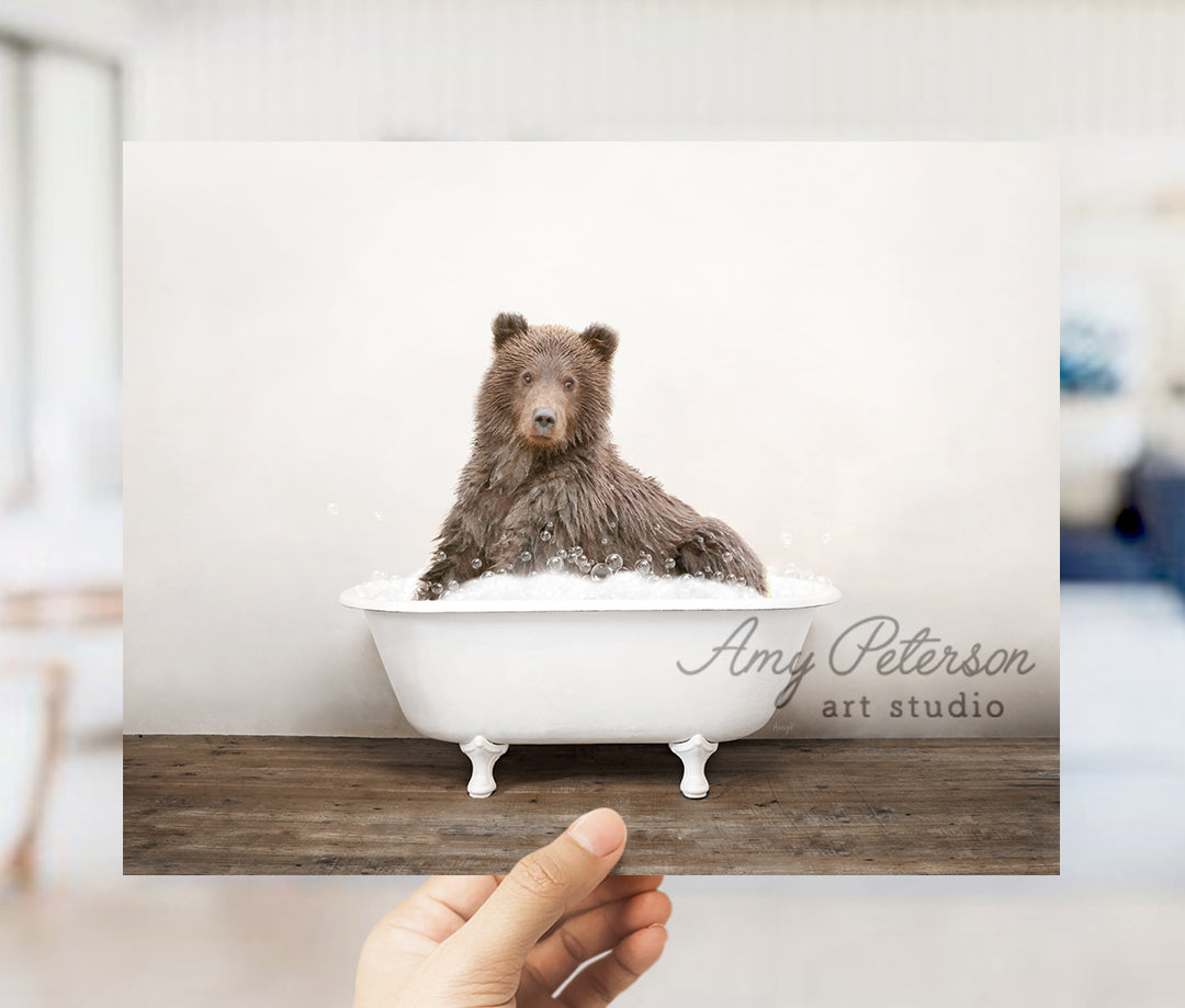 a person holding up a polaroid picture of a bear in a bathtub