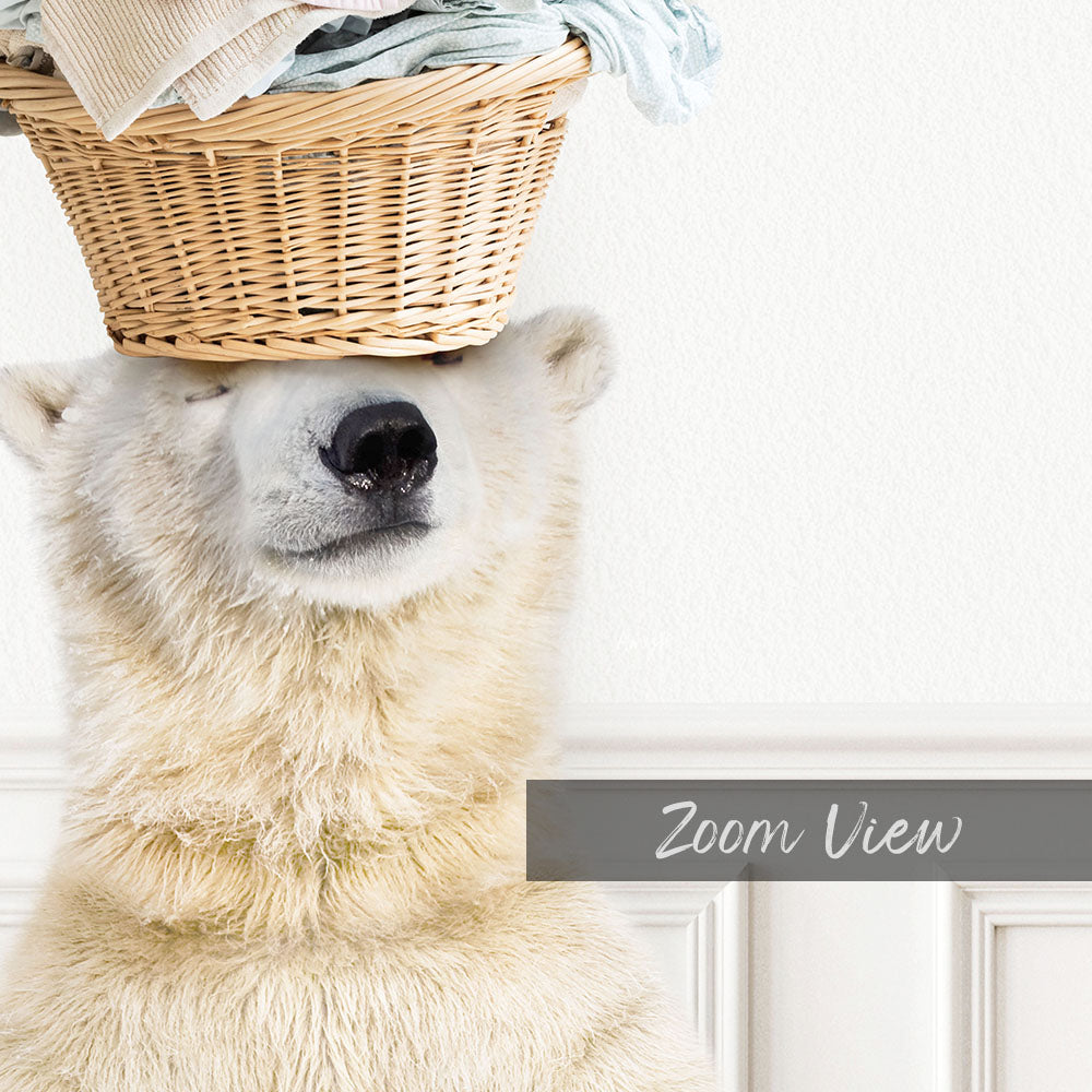 A polar bear is sitting in front of a white wall, with a basket of clothes placed on its head.