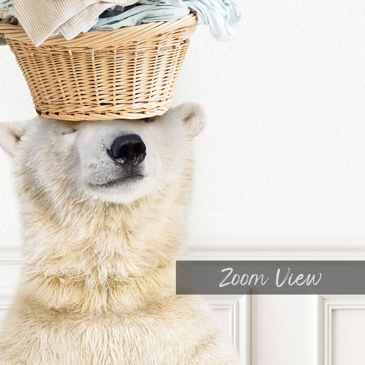 A polar bear is sitting in front of a white wall, with a basket of clothes placed on its head.