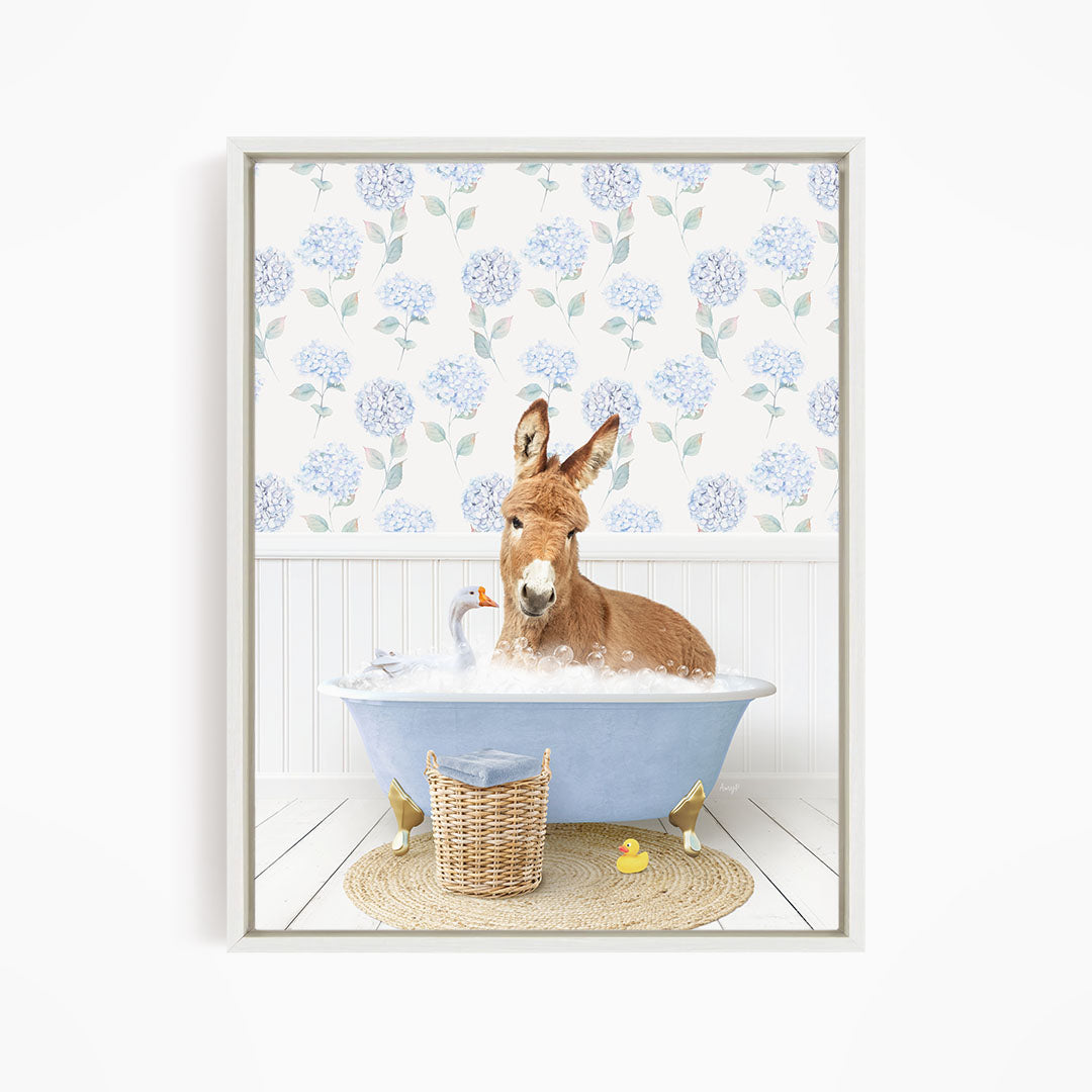 A donkey is sitting in a blue bathtub filled with bubbles, surrounded by a basket of rubber ducks and a white basket with a yellow duck.