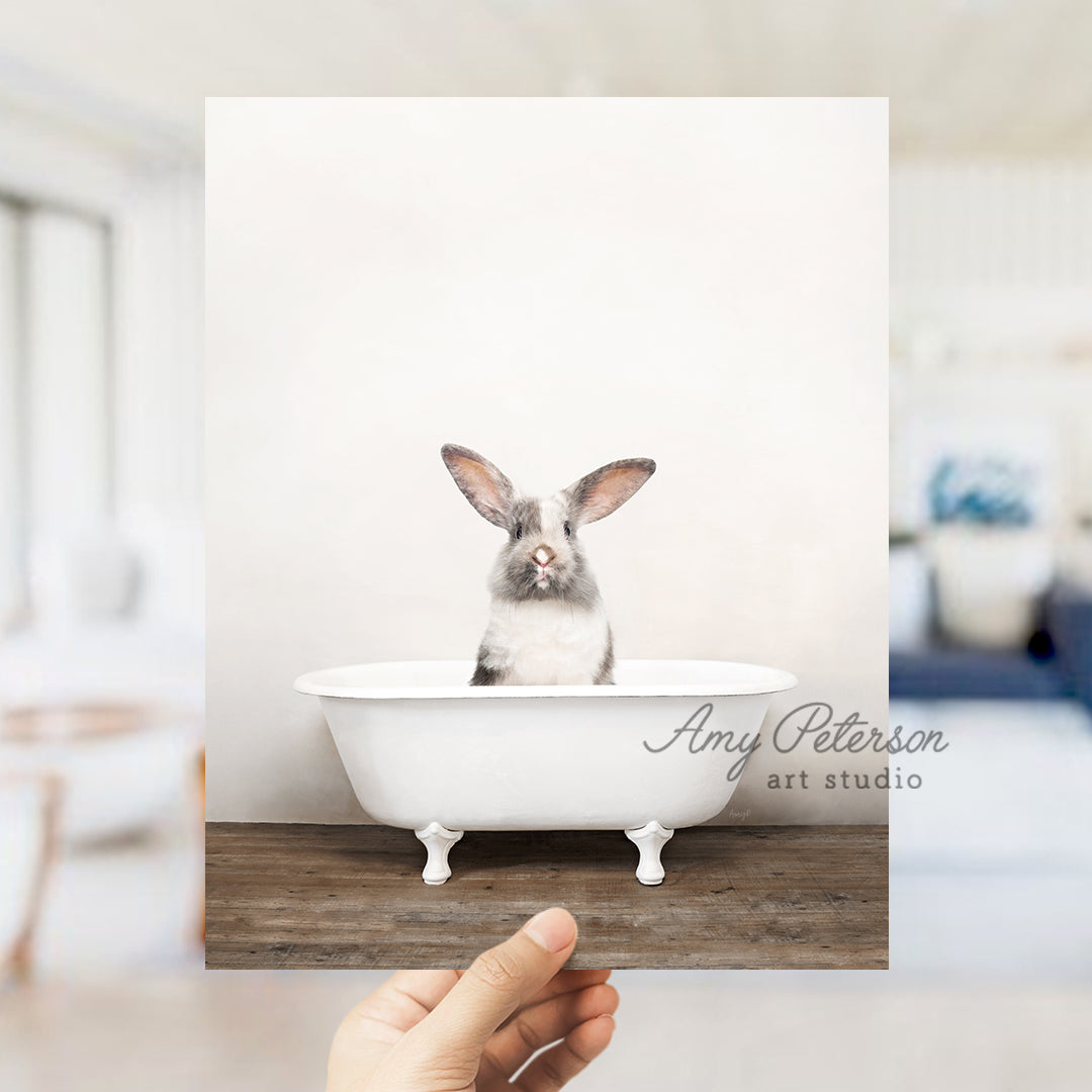 a person holding up a photo of a rabbit in a bathtub