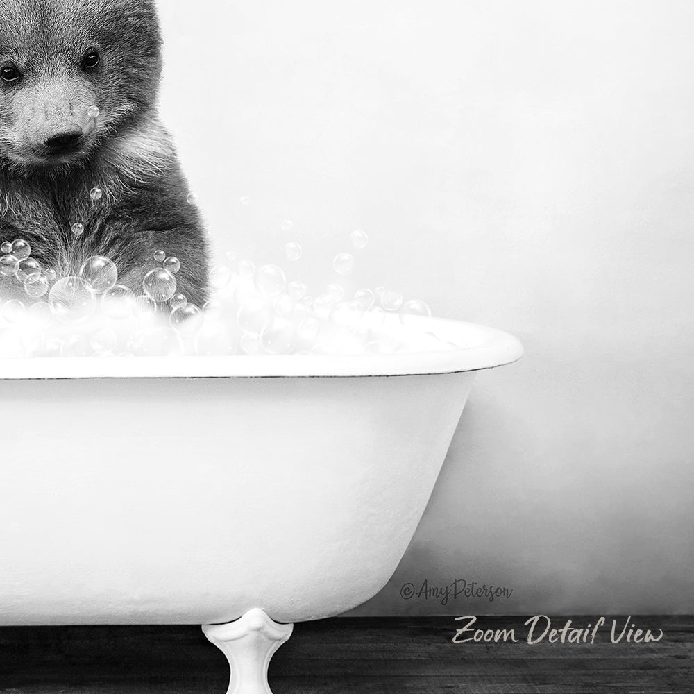 A black and white image of a bear sitting in a bathtub filled with bubbles.