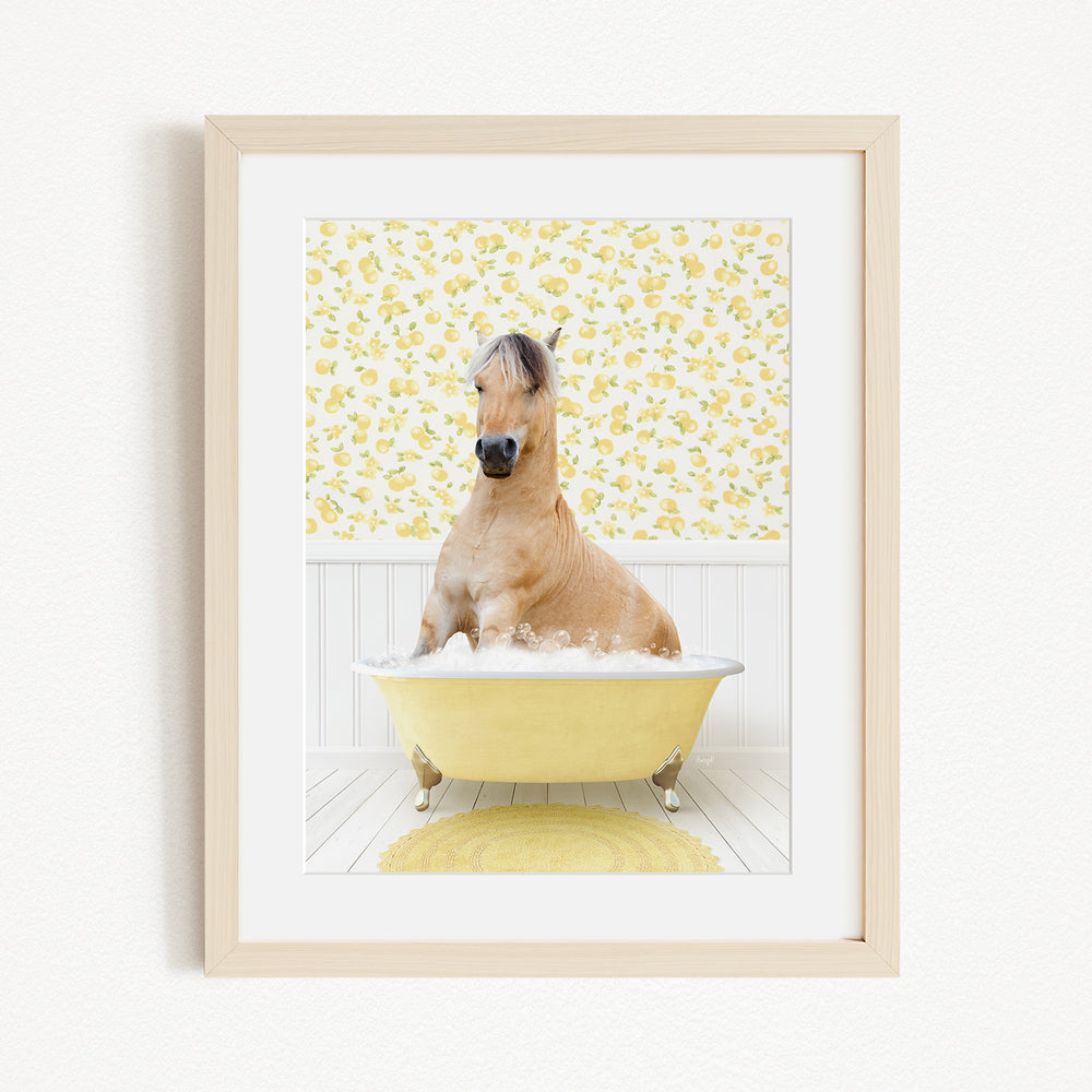 A light brown horse is sitting in a yellow bathtub filled with bubbles, surrounded by a yellow floral pattern on the wall behind it.