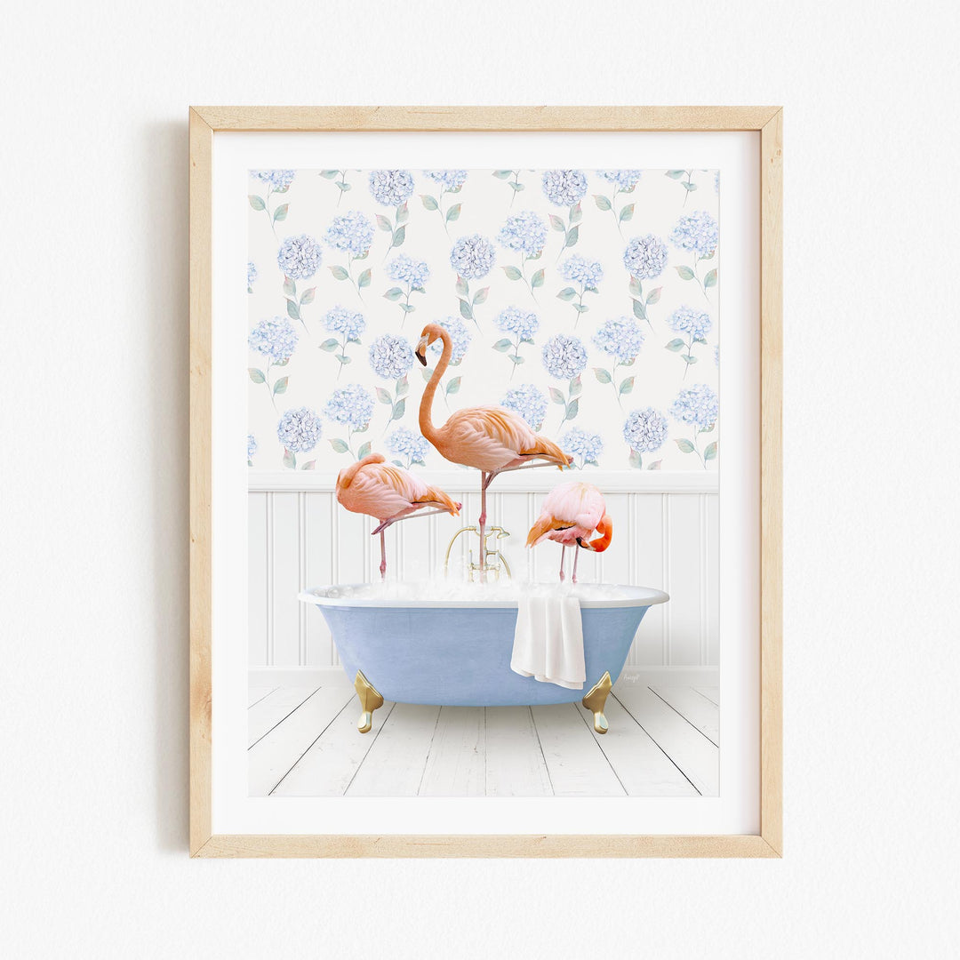 A framed image depicting three flamingos standing in a bathtub filled with bubbles, surrounded by a floral patterned wall.
