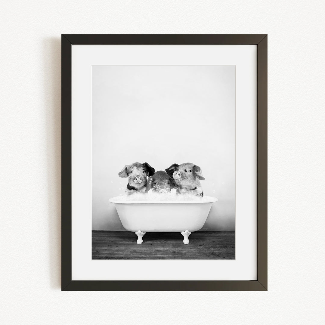 A black and white photograph of three small dogs sitting in a bathtub filled with water.