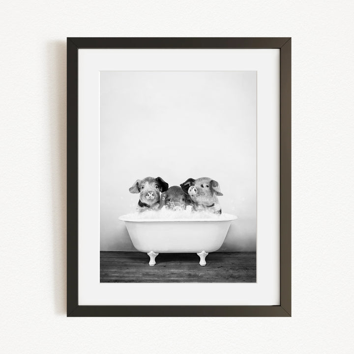 A black and white photograph of three small dogs sitting in a bathtub filled with water.