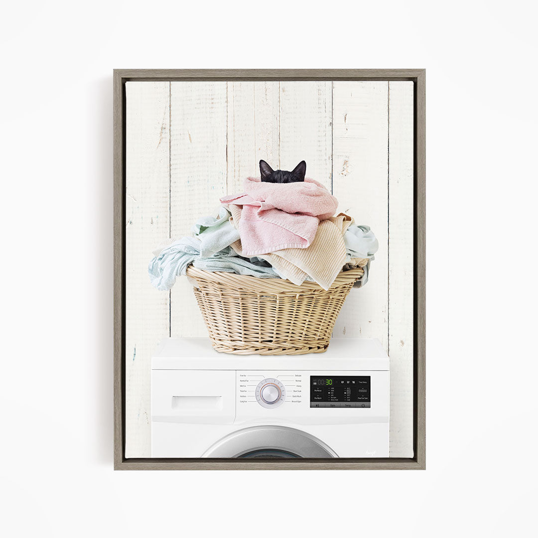 A cat is sitting on top of a basket filled with laundry, which is placed on a washing machine.