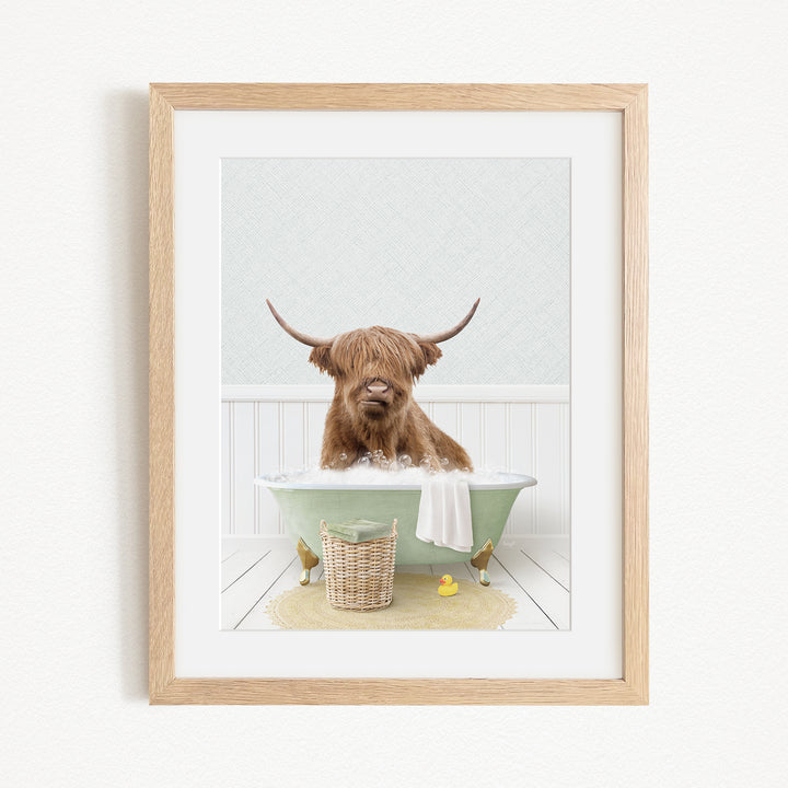 A Highland cow with long horns is sitting in a green bathtub, surrounded by a basket of rubber ducks and a yellow rubber ducky.