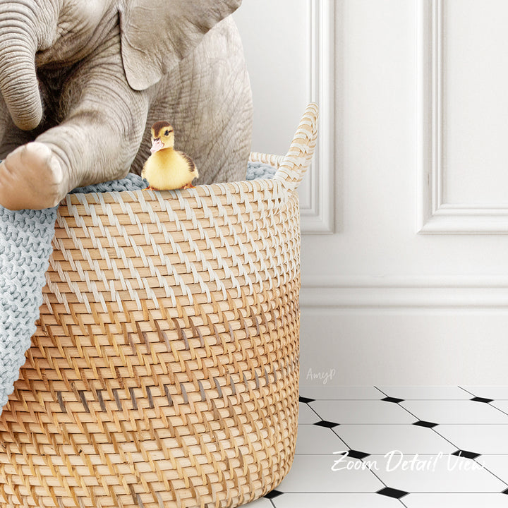 A small yellow duck sits in a woven basket, with a larger elephant trunk resting on top of the basket.