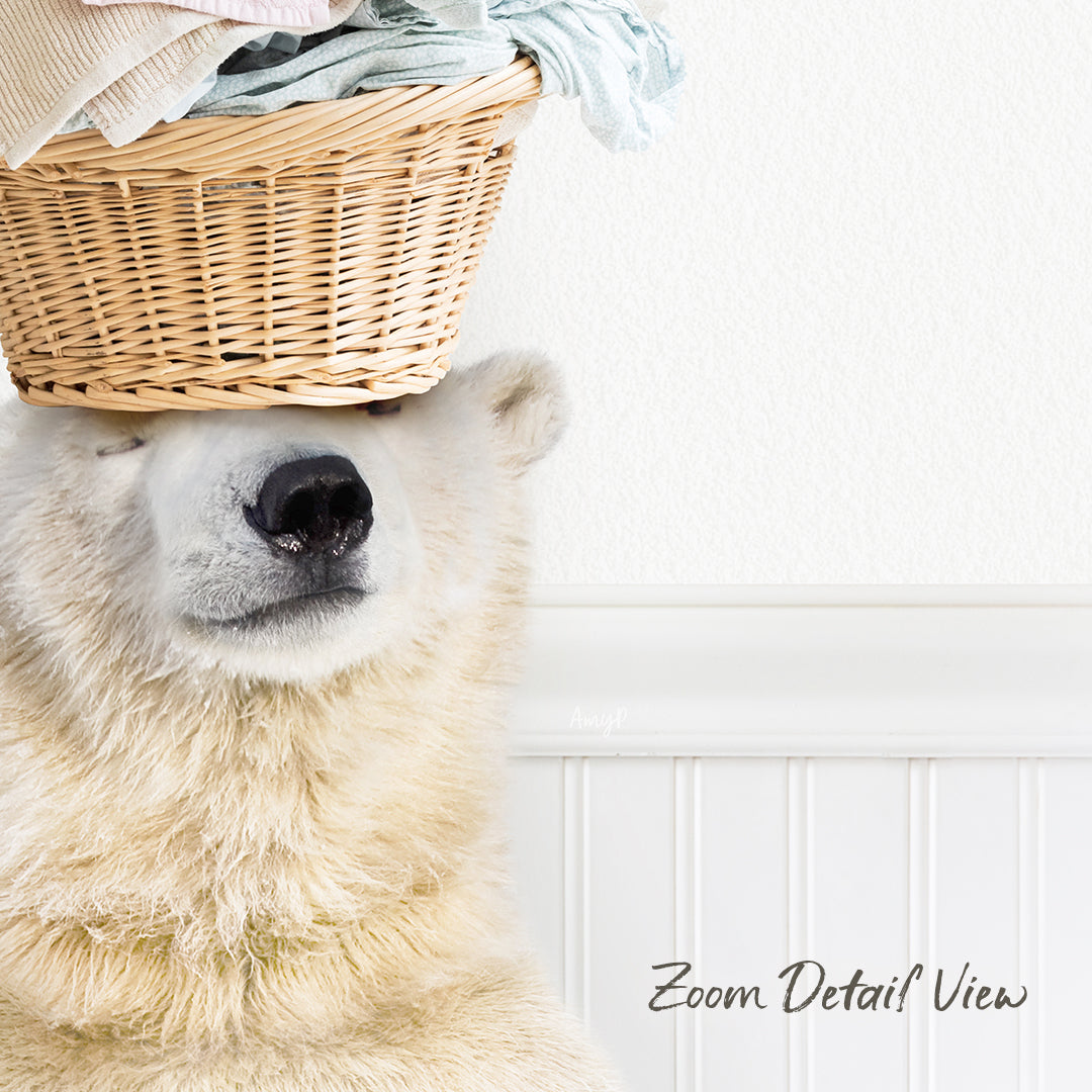 A polar bear sits in front of a basket filled with clothes, with its head resting on the basket.