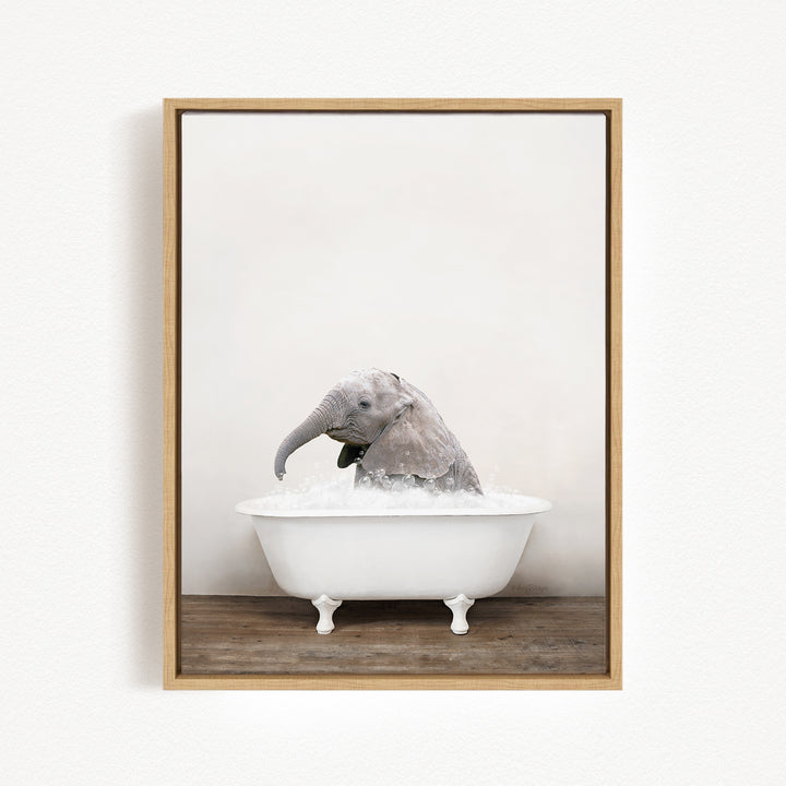 A baby elephant sitting in a white bathtub filled with water, with its trunk submerged in the water.