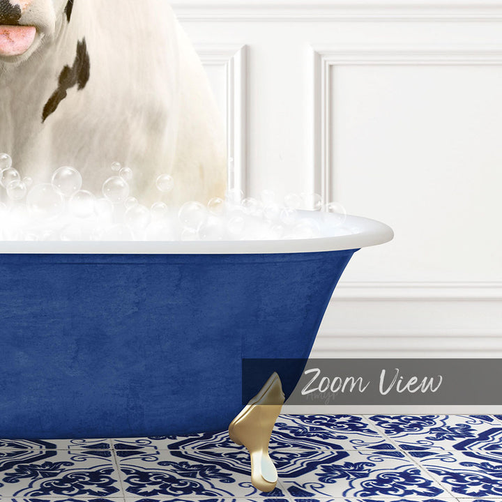 A white cow with black spots is standing in a blue bathtub filled with bubbles, with a white wall and a patterned tile floor in the background.
