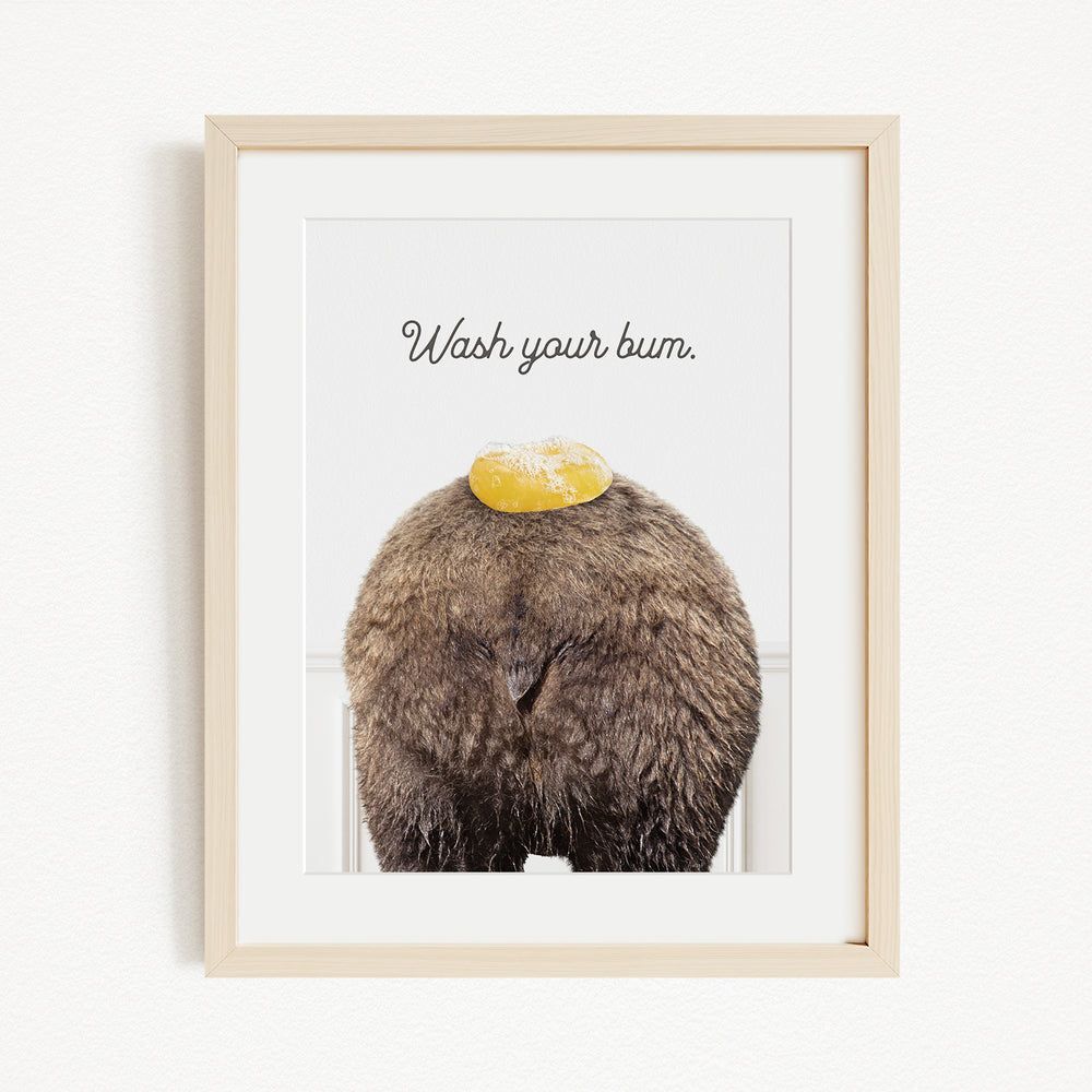 A framed image of a bear with a yellow object on its head, accompanied by the text "Wash your butt."