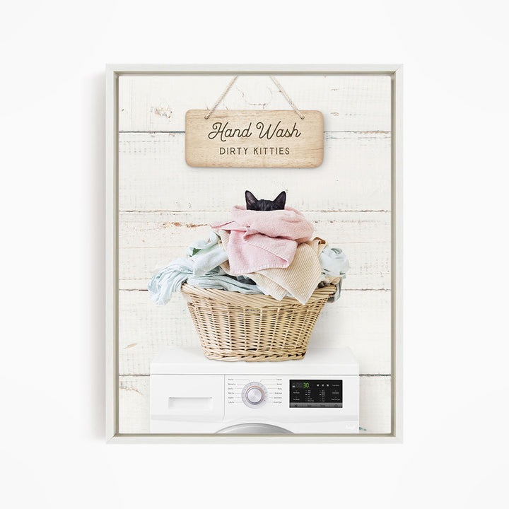 A framed image depicting a cat sitting in a basket filled with laundry, with a sign above that reads "Hand Wash Dirty Kittens".
