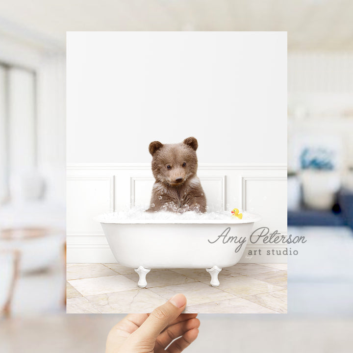 a person holding up a card with a teddy bear in a bathtub