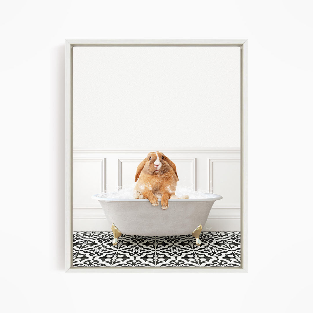 A brown rabbit sitting in a white bathtub filled with bubbles, surrounded by a black and white patterned floor.