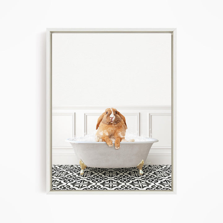 A brown rabbit sitting in a white bathtub filled with bubbles, surrounded by a black and white patterned floor.