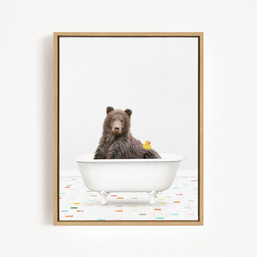 A brown bear sitting in a white bathtub, with a yellow rubber duck floating next to it.