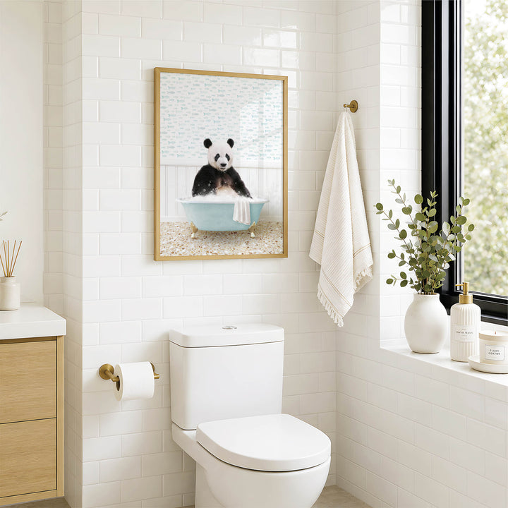 A bathroom with a white toilet, a framed picture of a panda sitting in a bathtub, and a window with greenery outside.