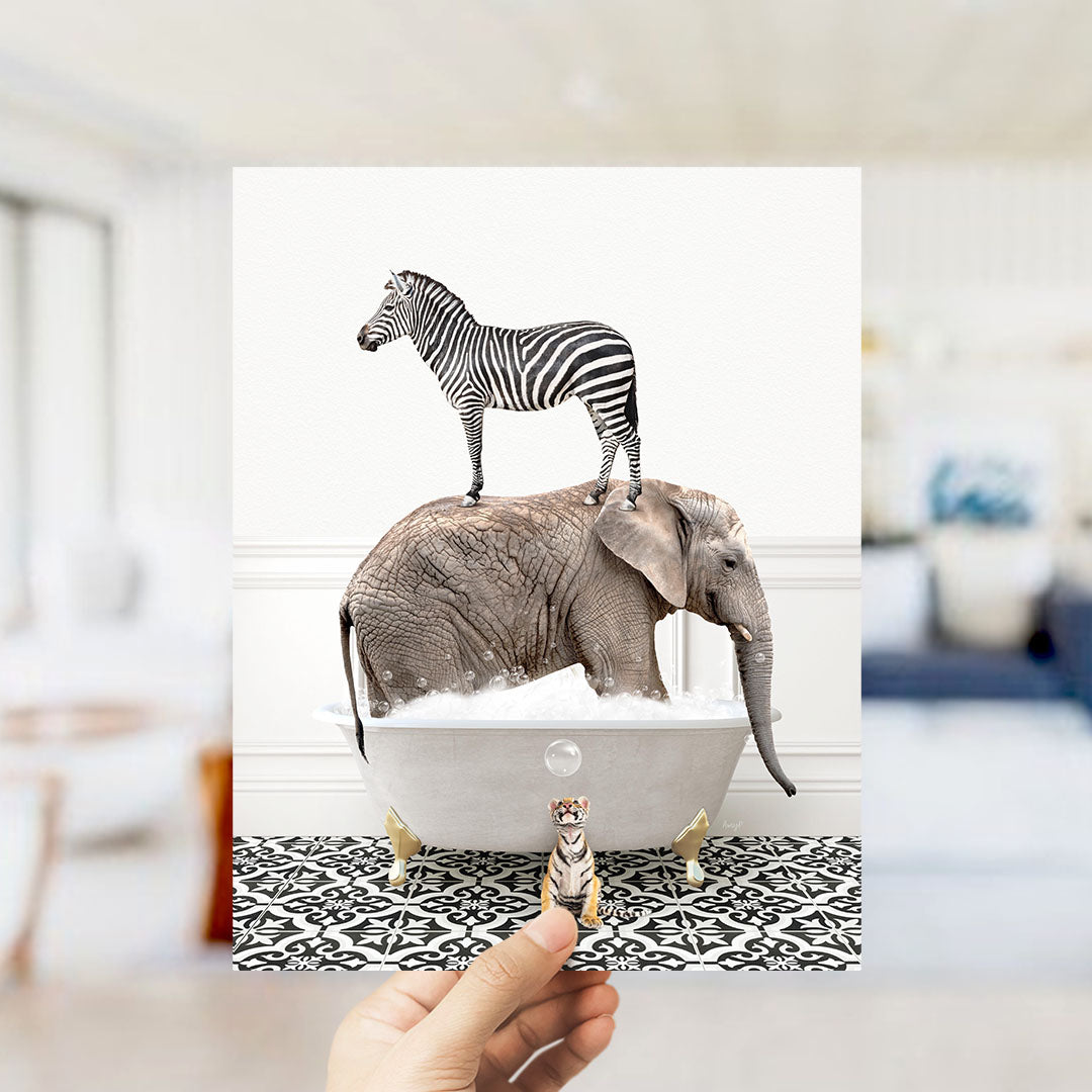 A hand holds up a collage of two images: a zebra standing on an elephant's back in a bathtub, and a small elephant standing in a bathtub with a bubble.