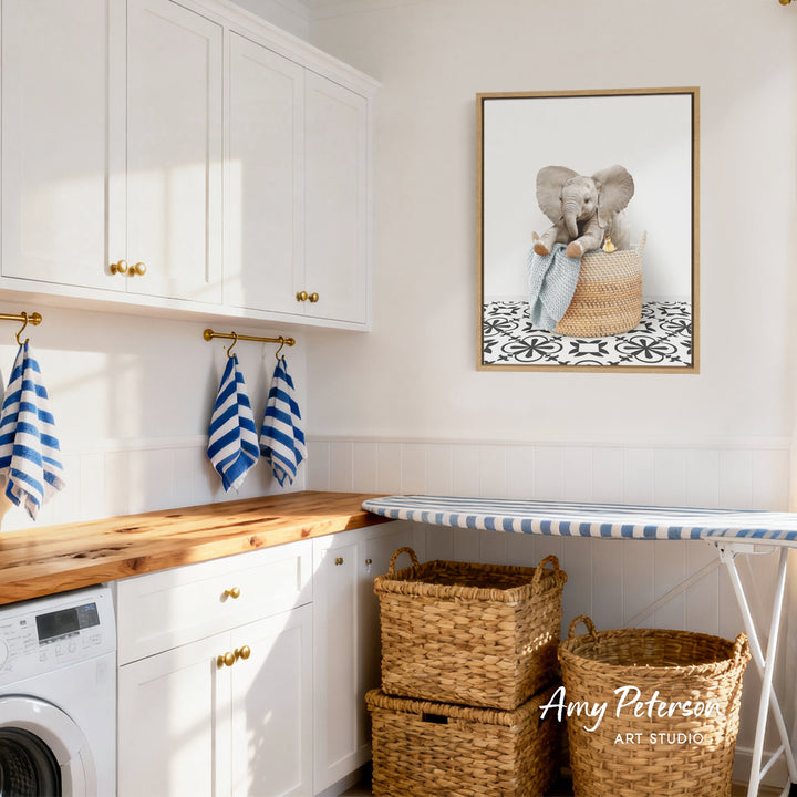 A cozy laundry room with white cabinets, a wooden countertop, and a framed image of an elephant sitting in a basket.